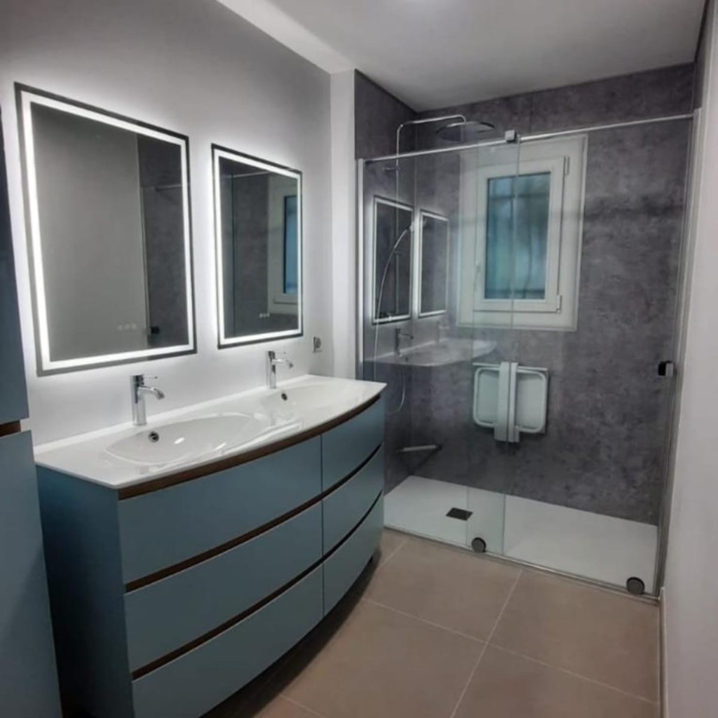 Salle de bain avec meuble bleu et douche à l'italienne